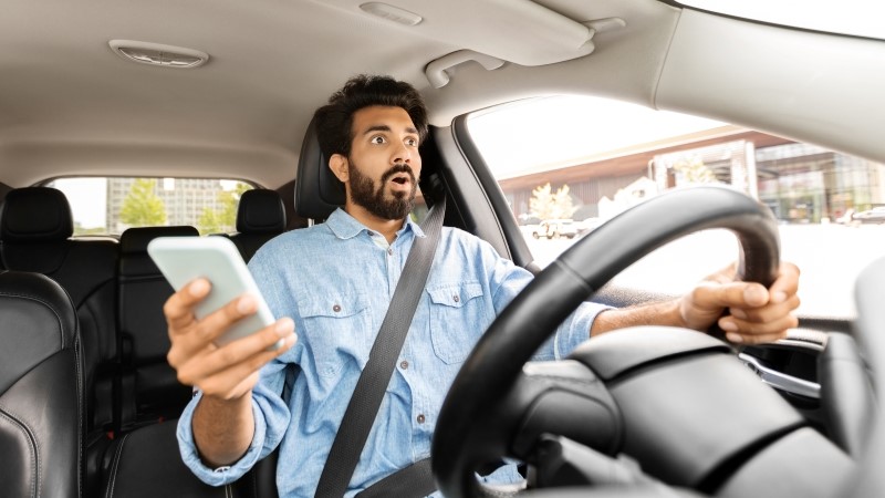 Guy holding phone in his hand, crushed automobile