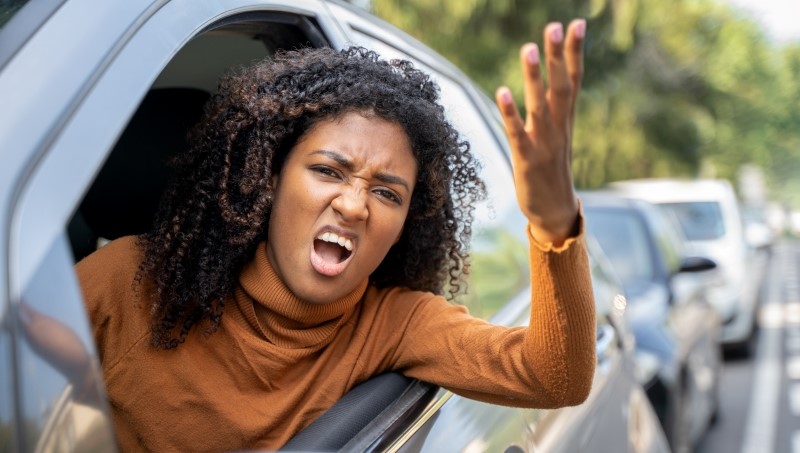 Aggressive woman driving car shouting at someone