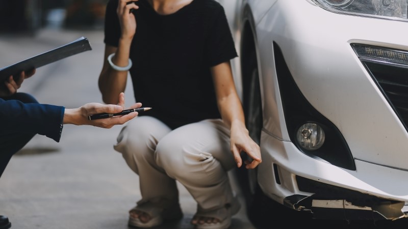 A young businesswoman is navigating car insurance options at her desk,