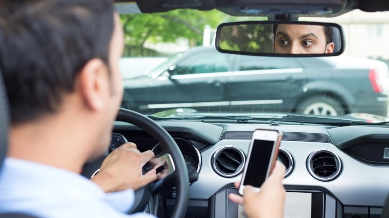 young man in blue polo shirt driving in black car and checking his phone, then shocked almost about to have traffic accident