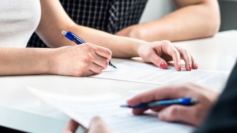 Settlement document signing. Bank loan contract or health insurance paper. Family paperwork. Home buyer debt or business agreement.