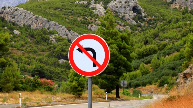 No left turns against beautiful mountains. Road prohibition sign,