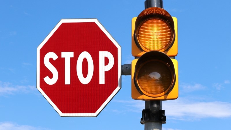 Traffic light with two flashing yellow lights accompanied by a stop sign isolated in the sky