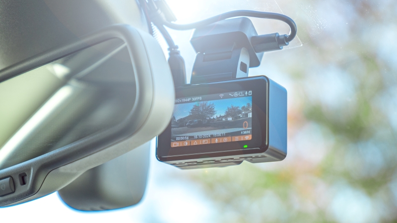 Close-Up Of Digital Camera On Windshield In Car. Dashcam mounted in the windshield with lens flare.