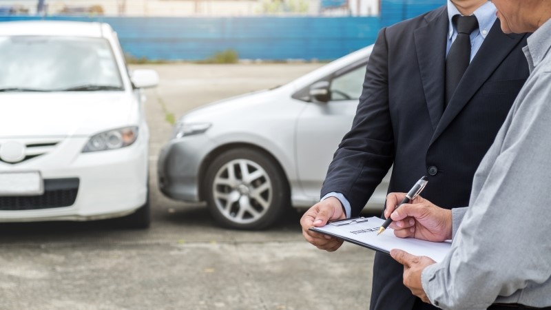 Insurance Agent examine Damaged Car and customer filing signature on Report Claim Form process after accident,