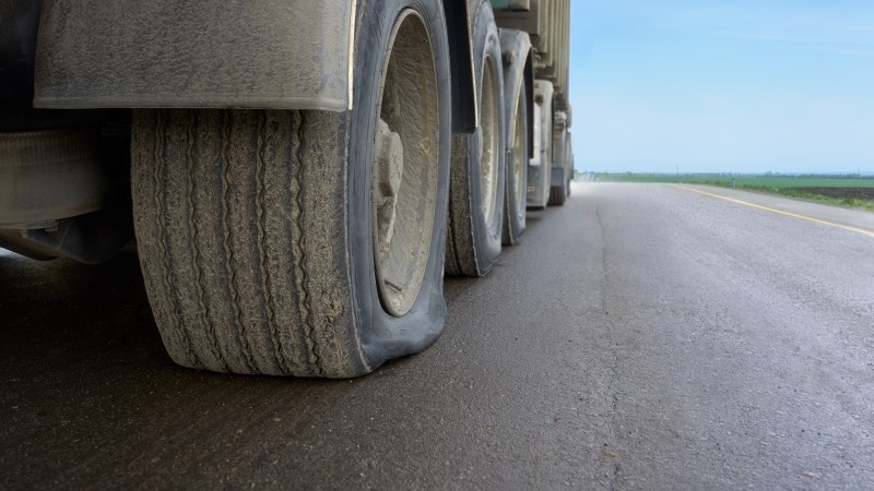 A flat tire on a large truck on a highway. View of a punctured truck wheel.