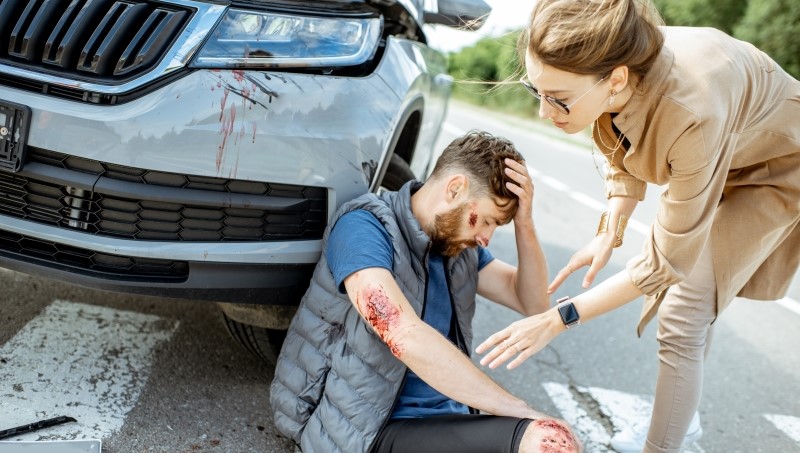 Woman driver feeling sorry about injured man suffering on the pedestrian crossing near the car after the road accident