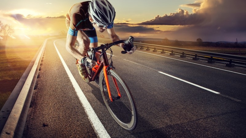 The cyclist rides on his bike at sunset. Dramatic background.
