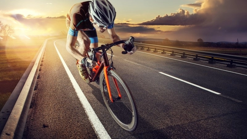 The cyclist rides on his bike at sunset. Dramatic background.