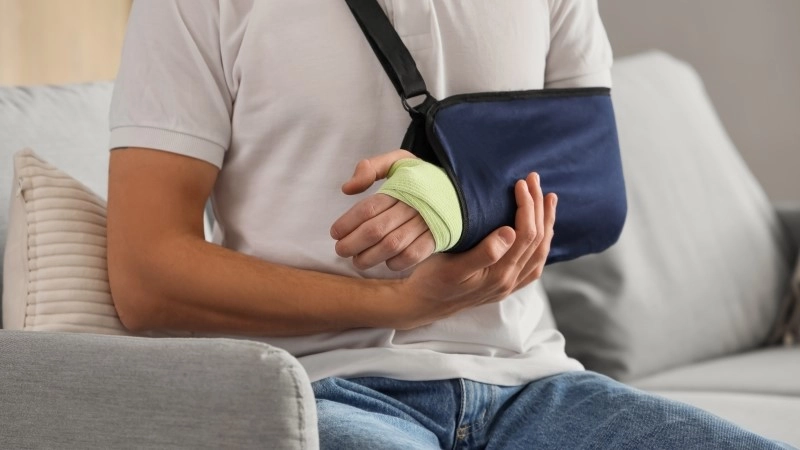 Injured young man after accident sitting on sofa at home,