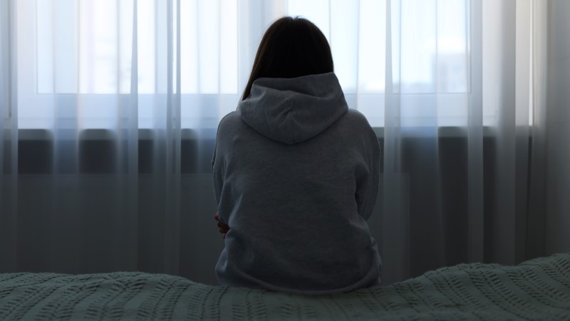 Loneliness concept. Sad woman sitting on bed at home