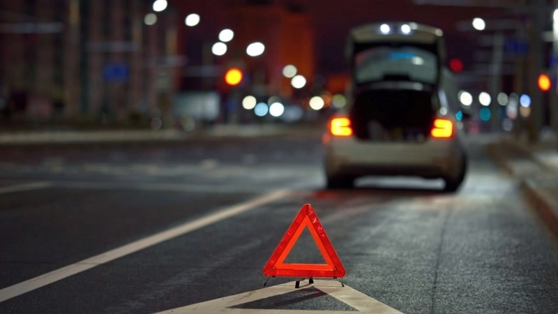 Broken down car on city street at night