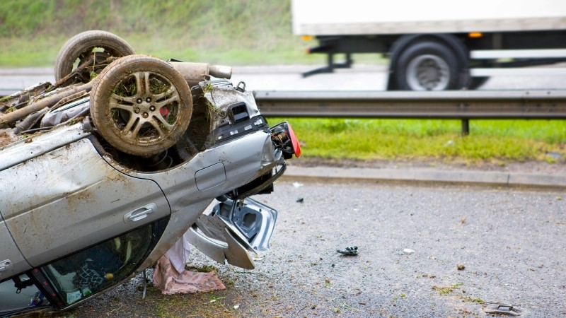 Close-up shot of the trunk of a car lying upside down after a crash on a motorway.