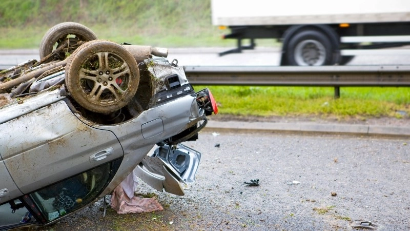 Close-up shot of the trunk of a car lying upside down after a crash on a motorway.
