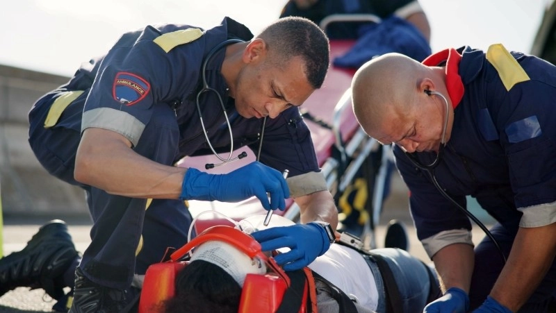 People, accident and emergency on road with flashlight for pupil response, head trauma or life support with check.