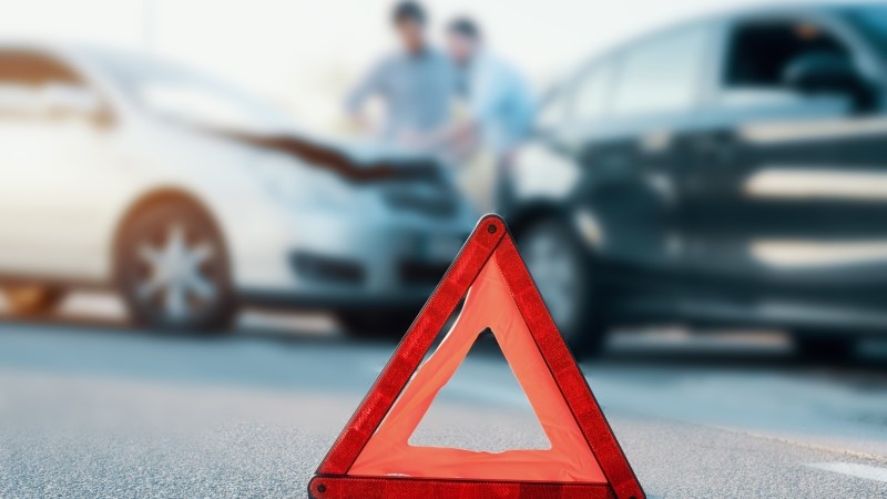 Two men reporting a car crash for the insurance claim,main focus on red triangle