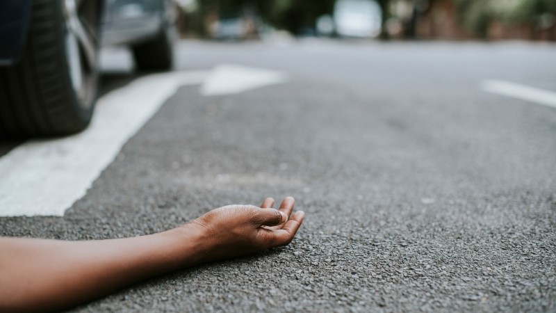 Person lying on the ground after a car accident