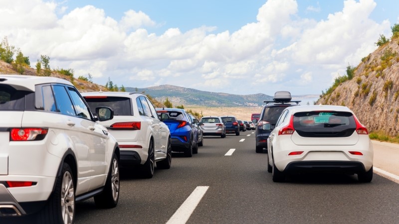 Back tail view of many cars stuck in row at highway road