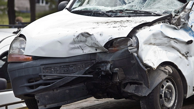 severely damaged van with crushed front end and shattered windshield after collision