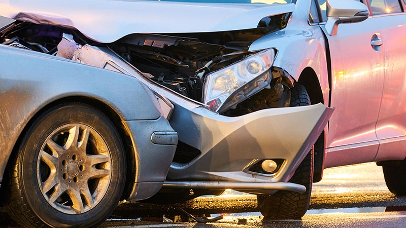Two vehicles with severe front-end damage after head-on collision on roadway