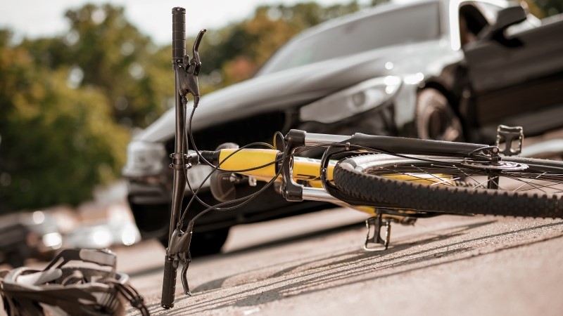 Bicycle and helmet lying on road and car