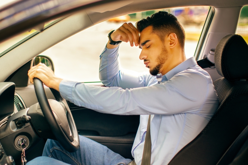 Car accident concept. Upset arab businessman driver sitting at front seat and touching his head, having automobile crash.