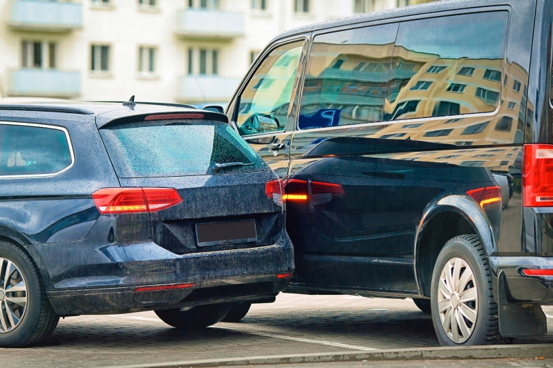 Rear-end collision in parking lot, collision between two cars, damaged rear bumper and door.