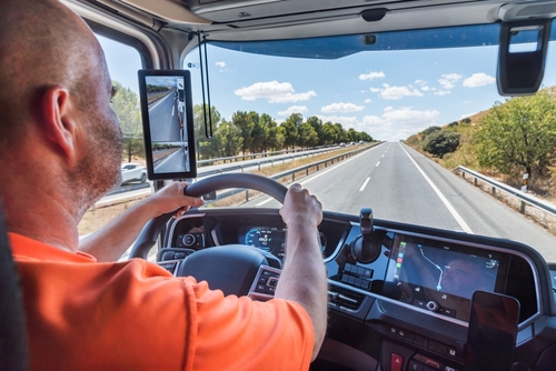 Truck driver holding steering wheel while driving on open highway from cab interior