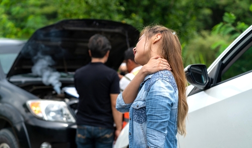 Woman seated in car touching neck after apparent traffic collision