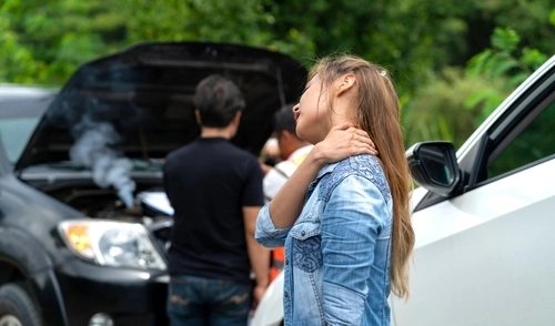 Woman seated in car touching neck after apparent traffic collision
